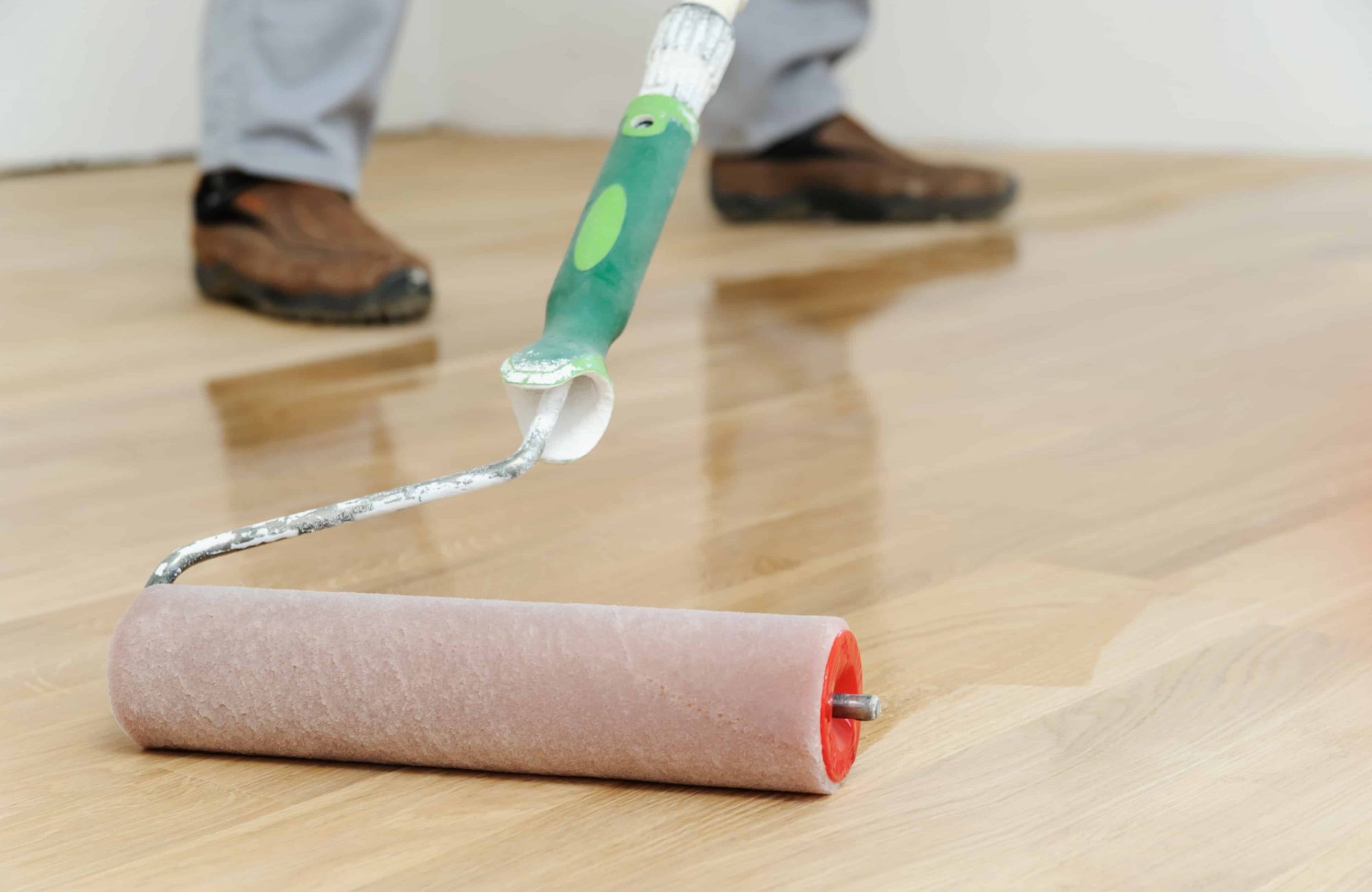 Lacquering wood floors. Use roller for coating floors.